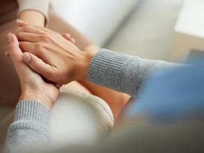 A person holding another person's hand in a compassionate way