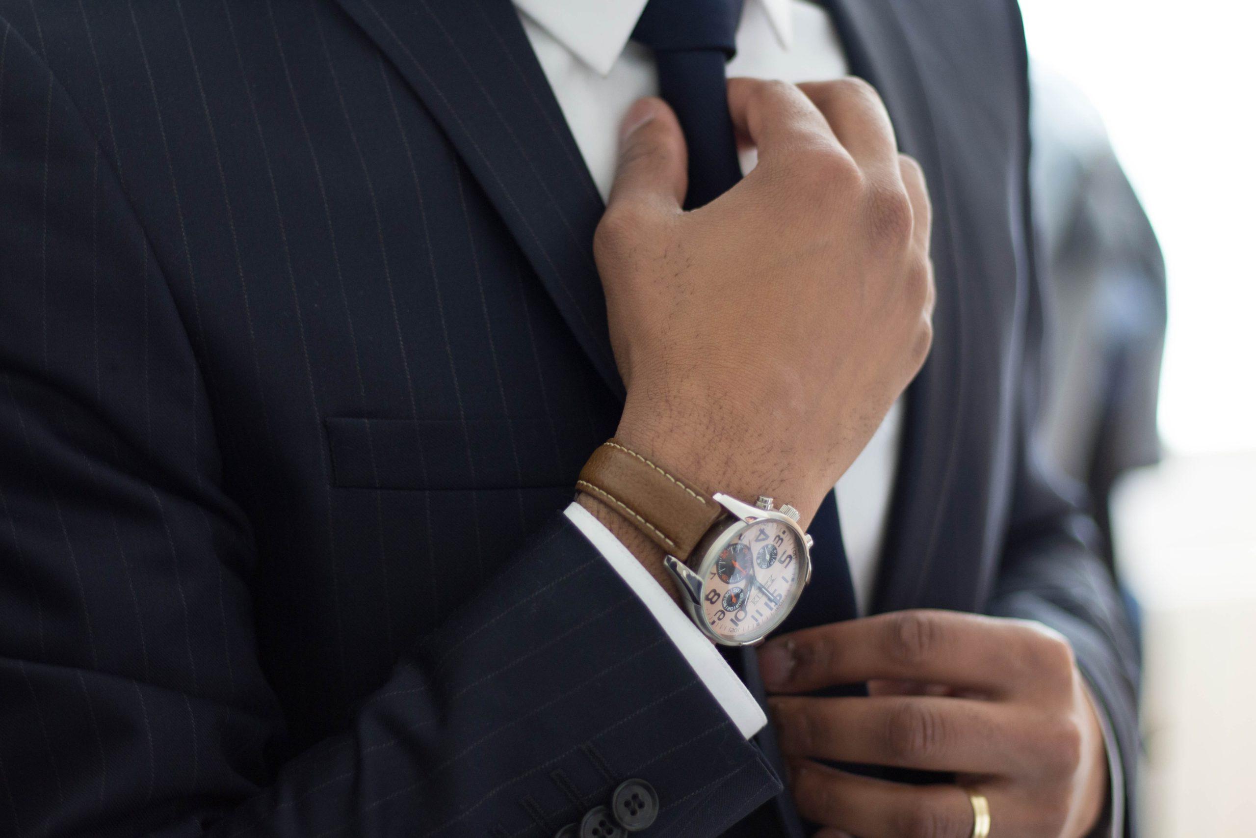 A person wearing a watch adjusting their tie