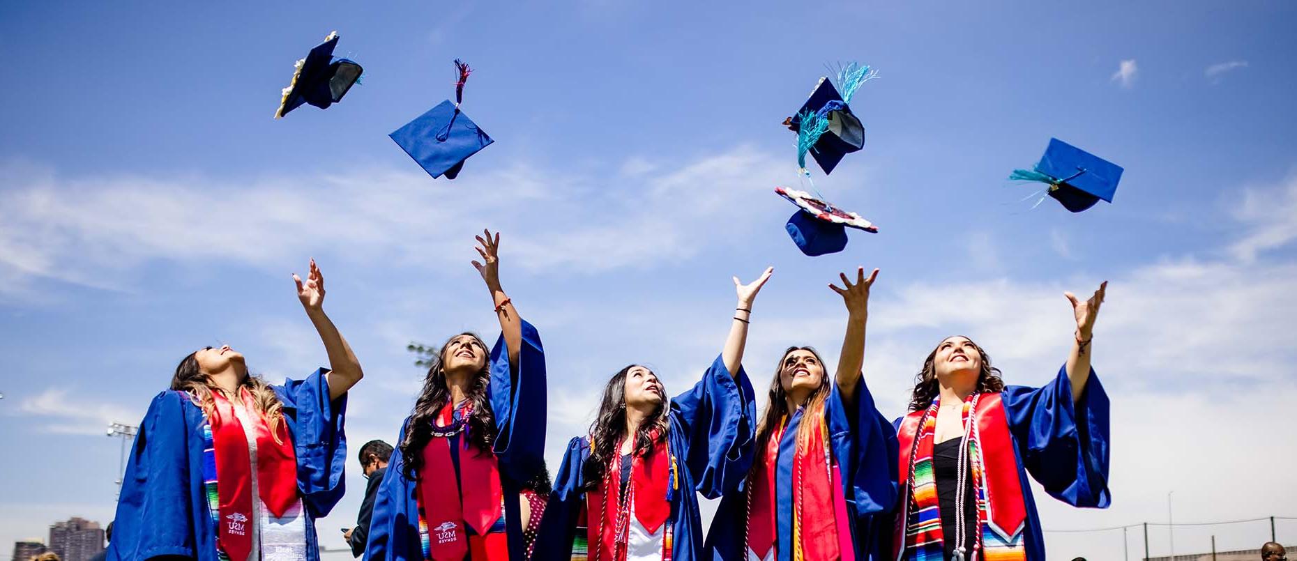 密歇根州立大学丹佛 graduates throwing their caps in the air.