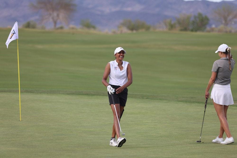 一名密歇根州立大学丹佛女子高尔夫运动员微笑着走下果岭.