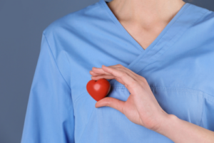 穿着手术服的人在心脏上拿着一个红色的压力球